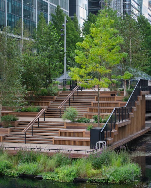 A multi-level outdoor garden area featuring wide wooden steps with black metal handrails that serve as seating or walking paths, surrounded by lush greenery including various trees and shrubs with bri